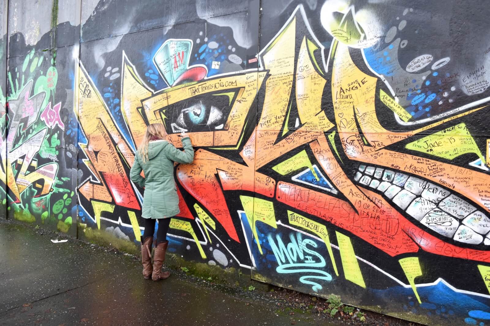 Hayley writing on the colourful peace wall in Belfast