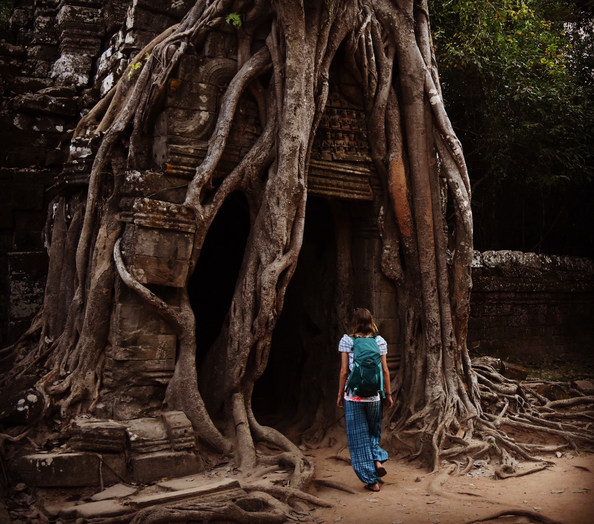 Hayley walking through a root covered gateway at Ta Som