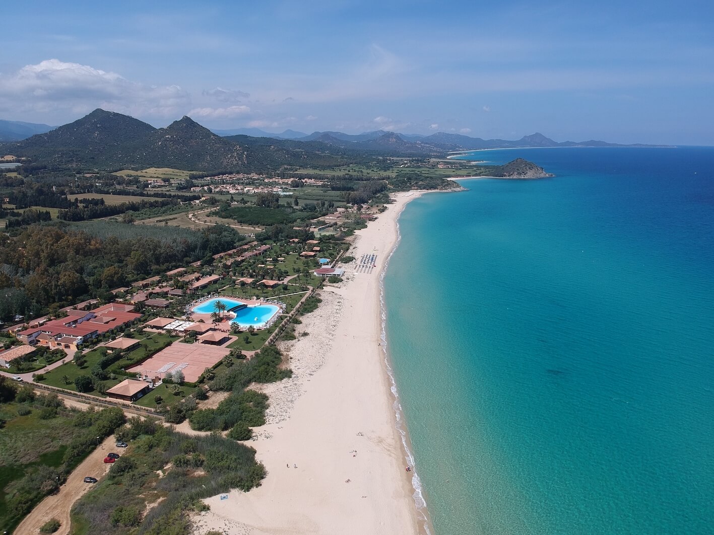 An aerial view of a white sand beach and turquoise water in Sardinia