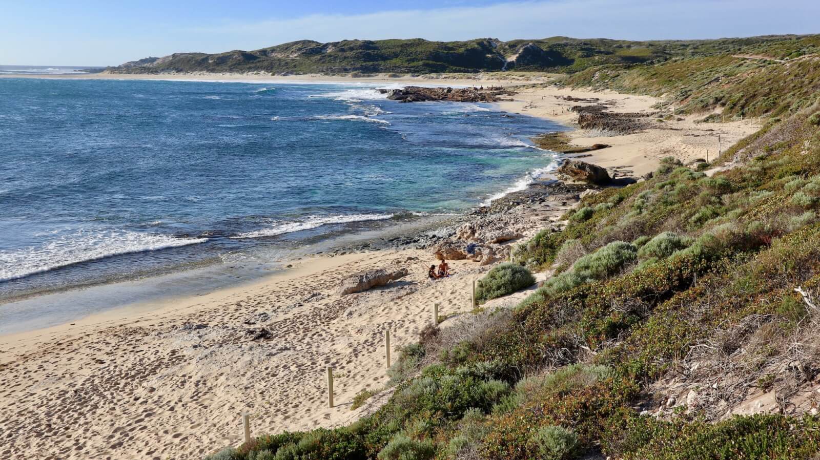 green scrub leading to white sand and blue ocean