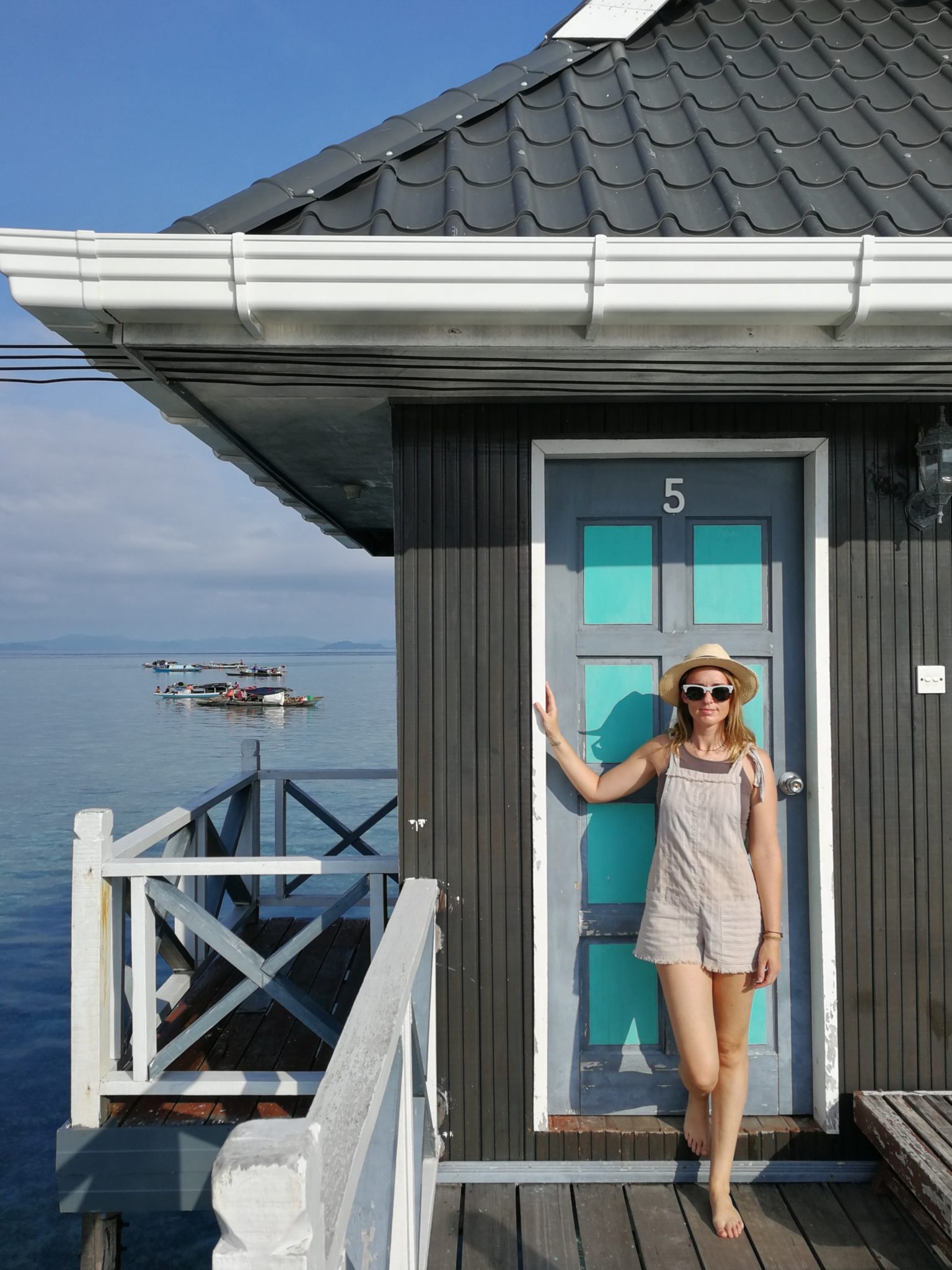 Sarah standing in front of a beach bungalow with a turquoise door