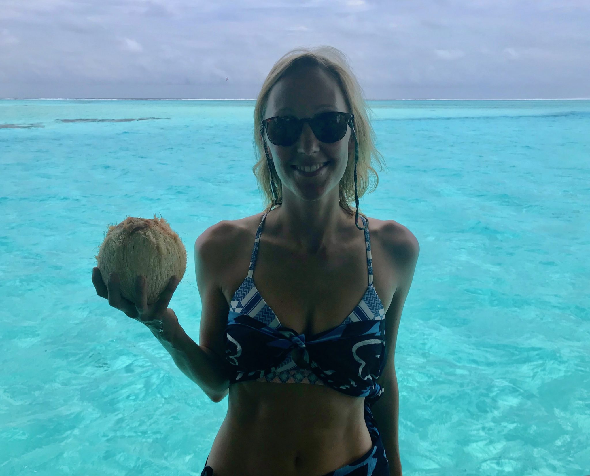 Hayley holding a coconut with clear blue ocean behind