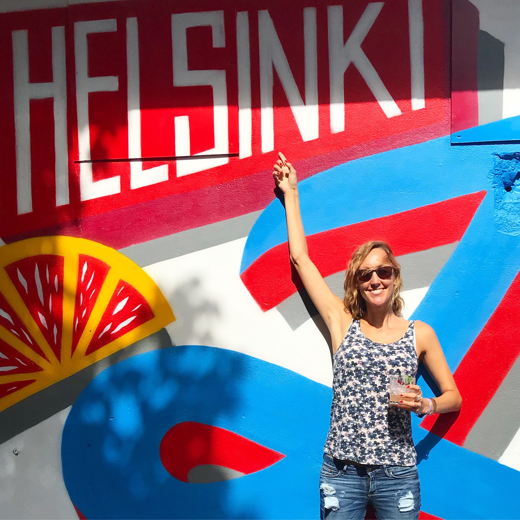 Hayley standing in front of a painted wall that says 'Helsinki' 