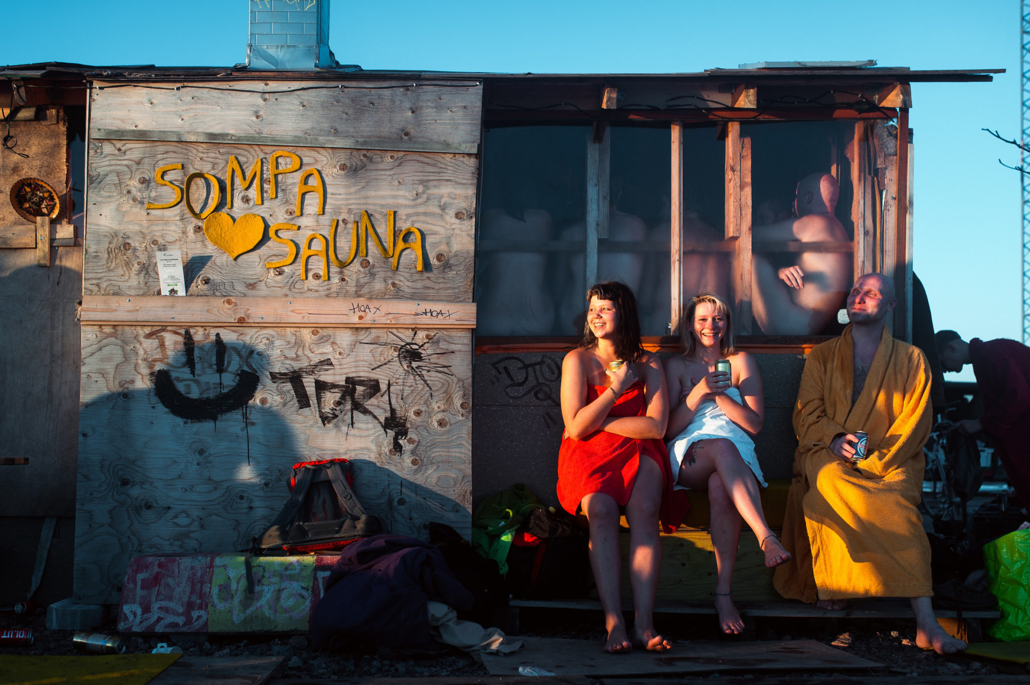 Three people enjoy a drink outside Sompa Sauna in Helsinki, Finland