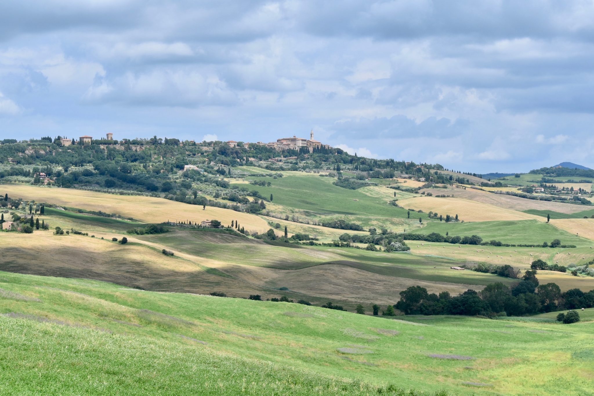 The rolling hills of Val d'Orcia in Tuscany with a hilltop town in the distance