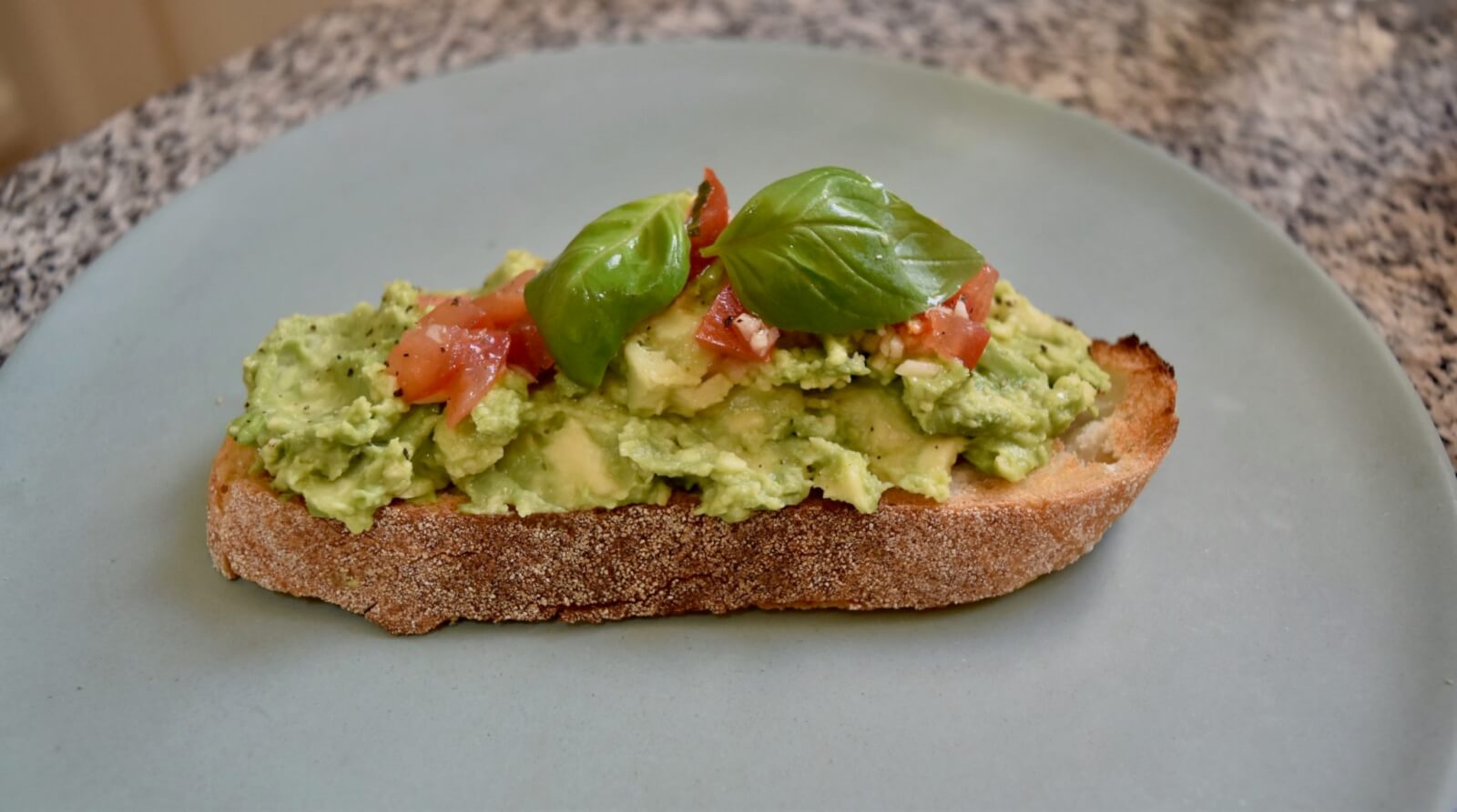 smashed avocado on toast served with basil and tomato