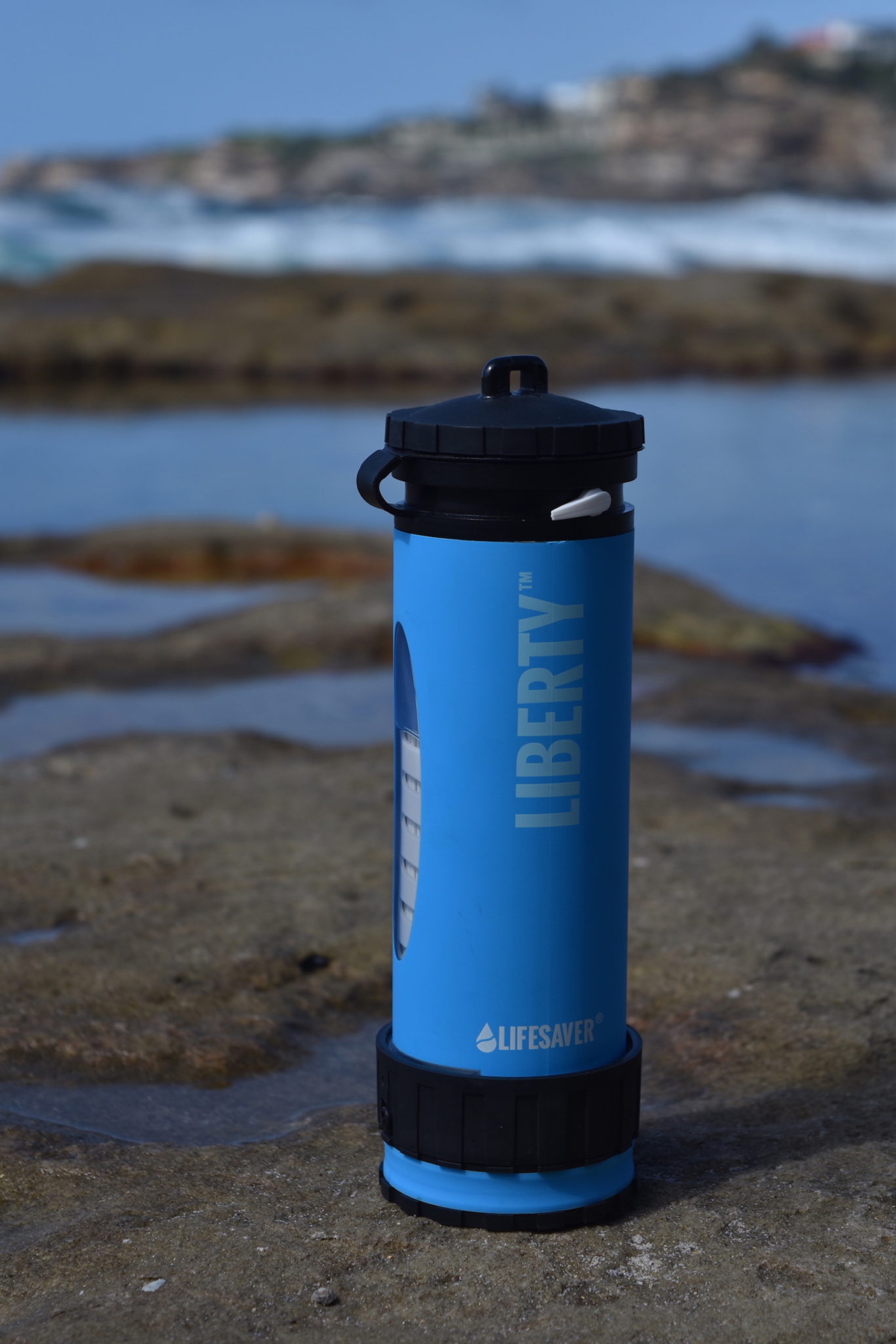 A blue filter water bottle on the rocks by the ocean