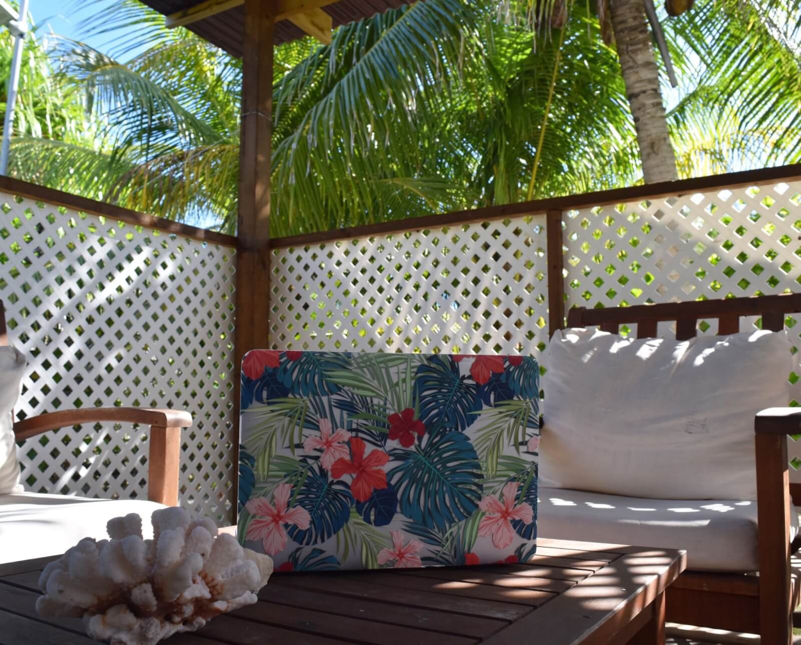 A table and chairs with a lap top surrounded by palms