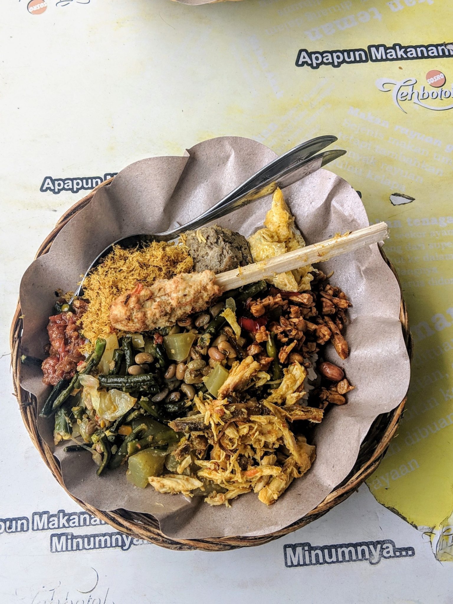 A dish of Nasi Campur - mixed rice dish with tempeh, veg, nuts and coconut shavings