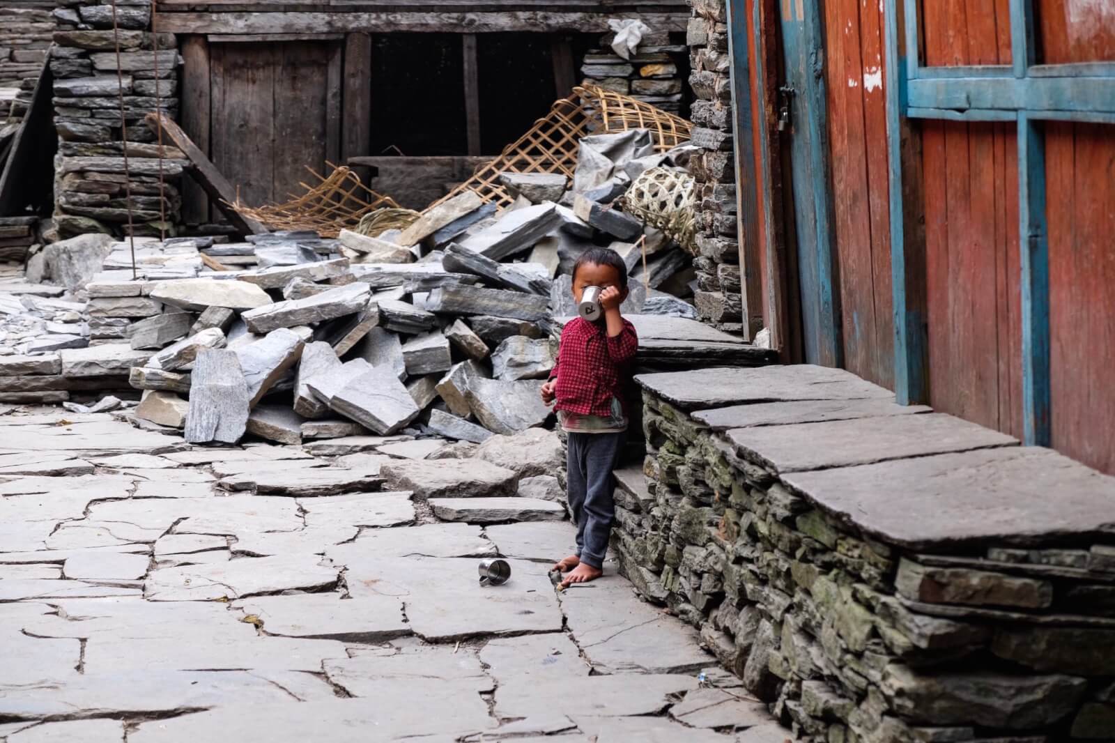 A child drinking out of a cup in a Nepalese village 