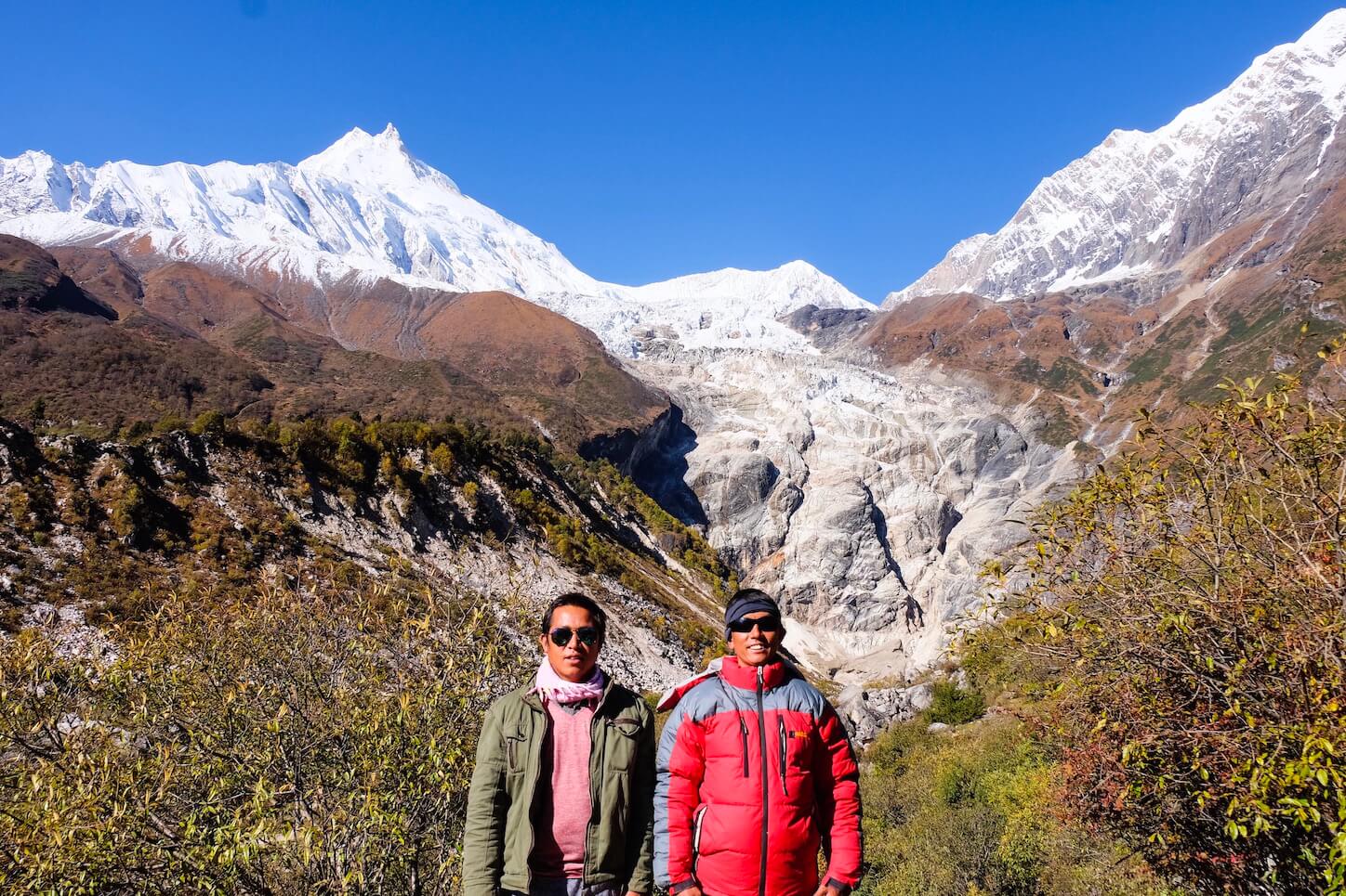 A Nepalese guide and porter in front of a mountain backdrop