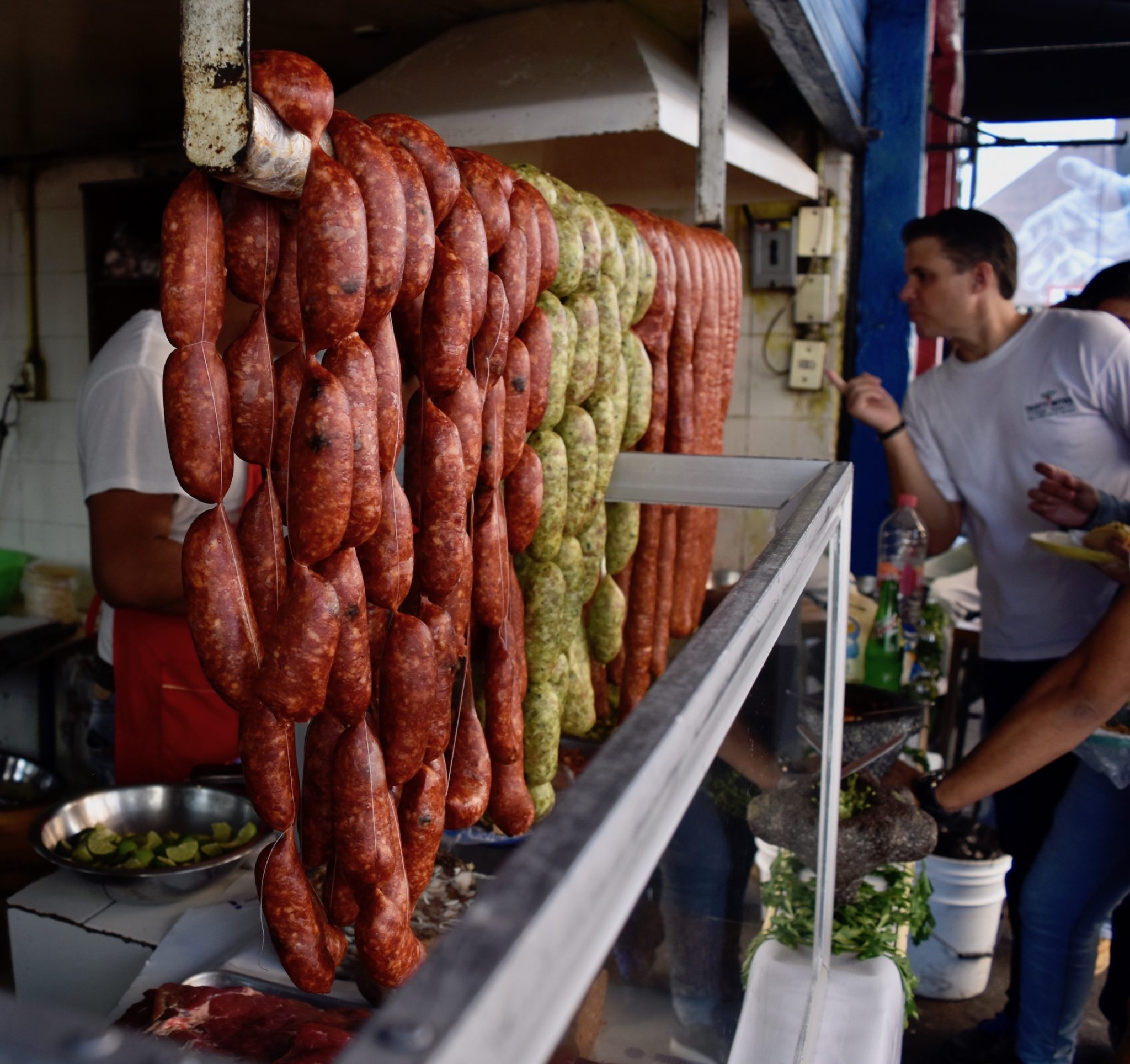Green and red chorizo hanging on a stall 