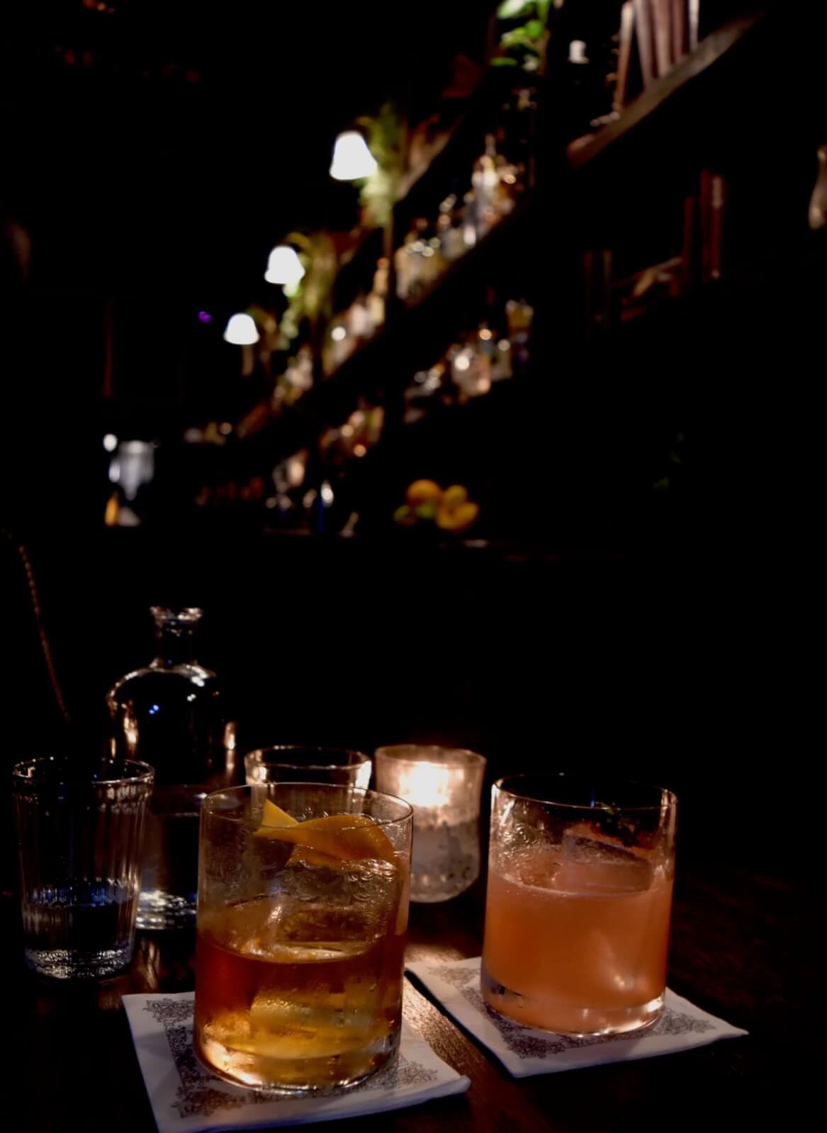 Two cocktails in front of a bar 