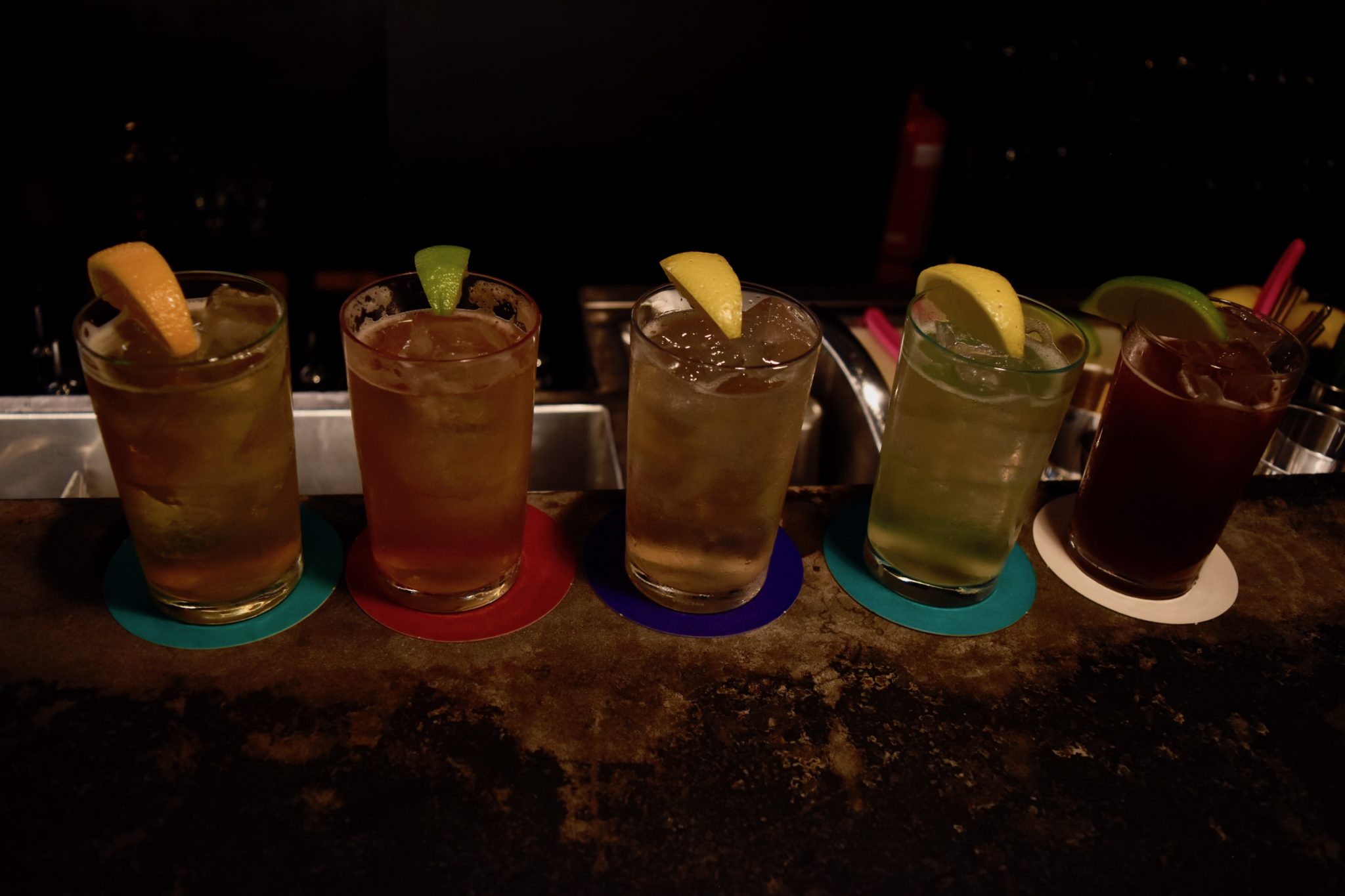 5 glasses filled with different colour sodas