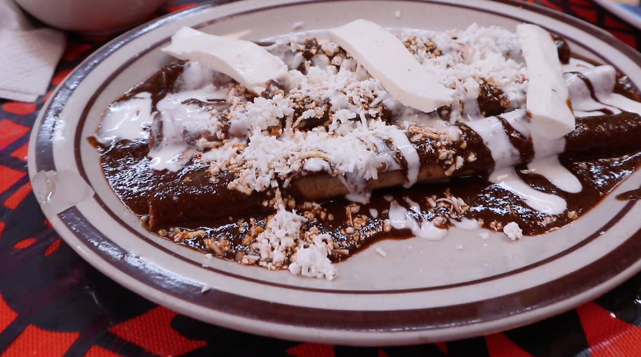 Rolled tortillas filled with meat and covered in a dark mole 