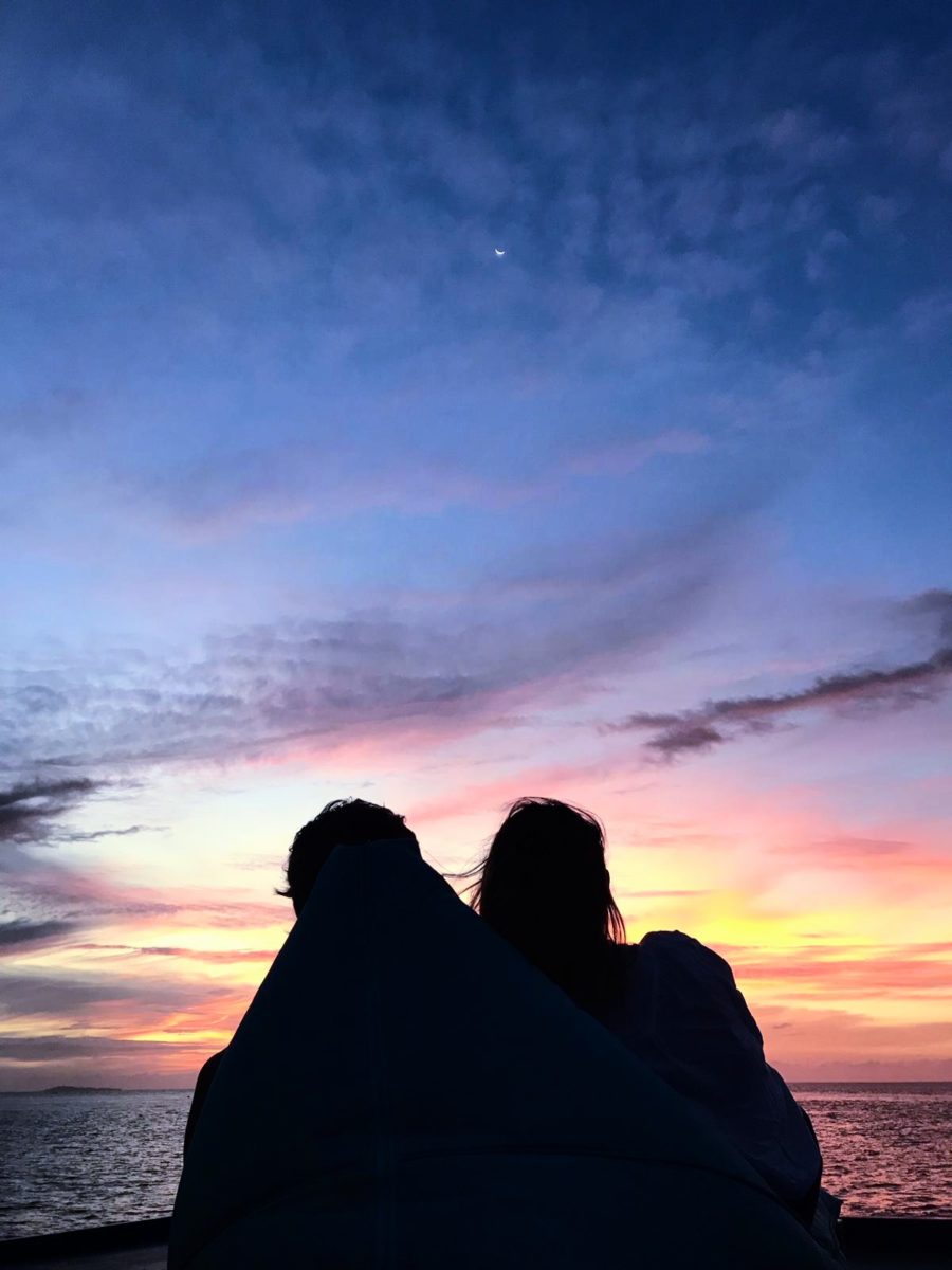 The silhouette of a couple against a colourful sunset