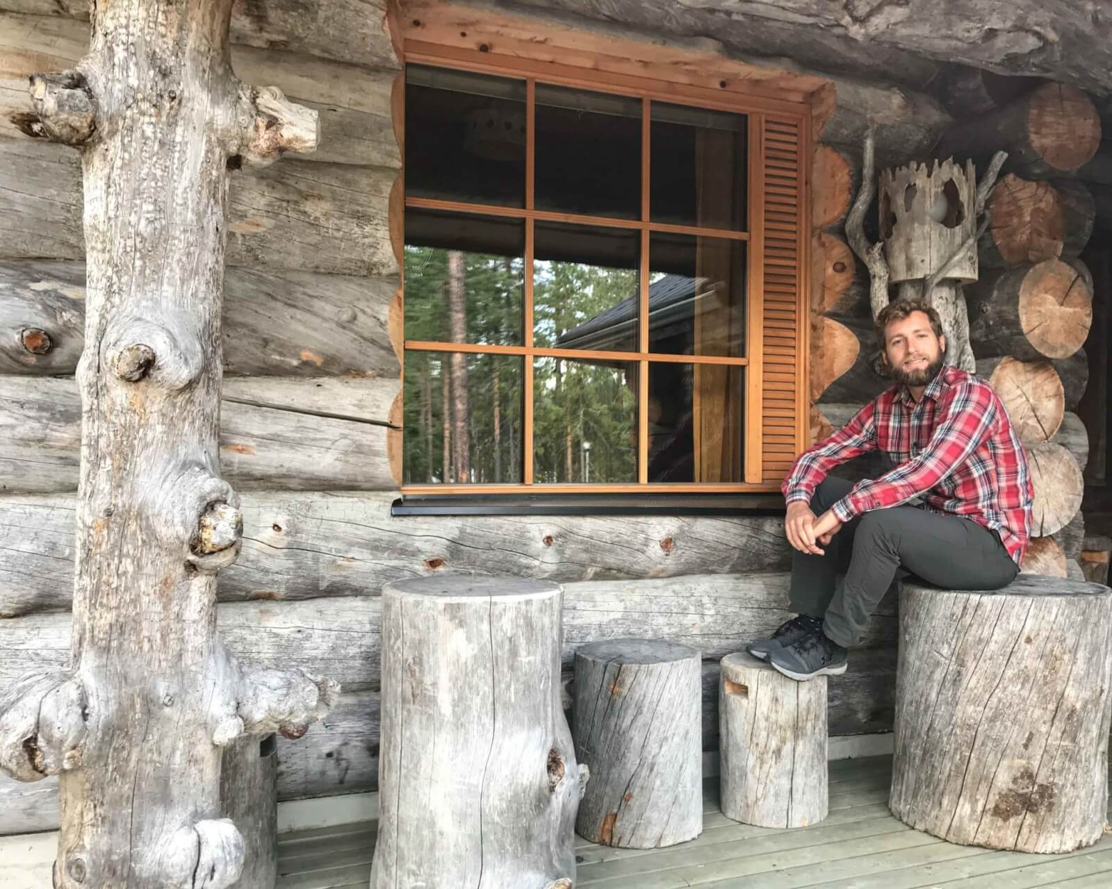 Enrico sitting on a log outside our wood cabin