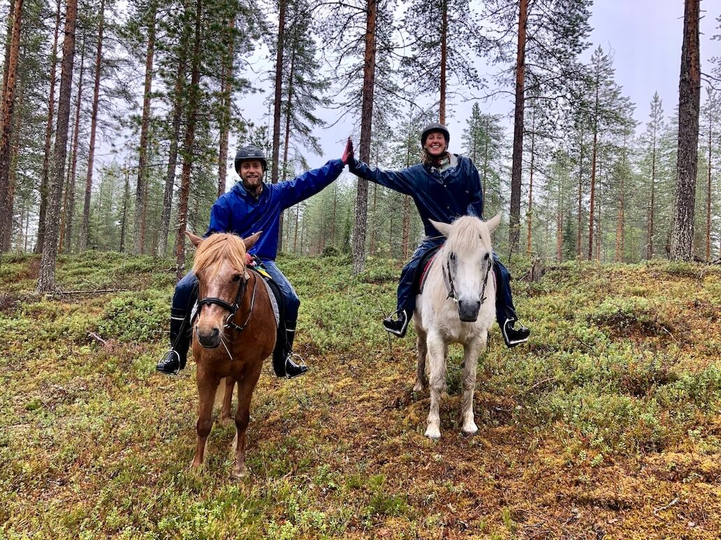 Hayley and Enrico high fiving on horse back in Finland Lapland