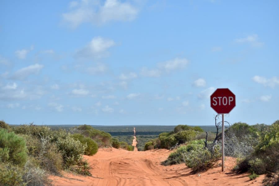 A red sandy road with a stop sign