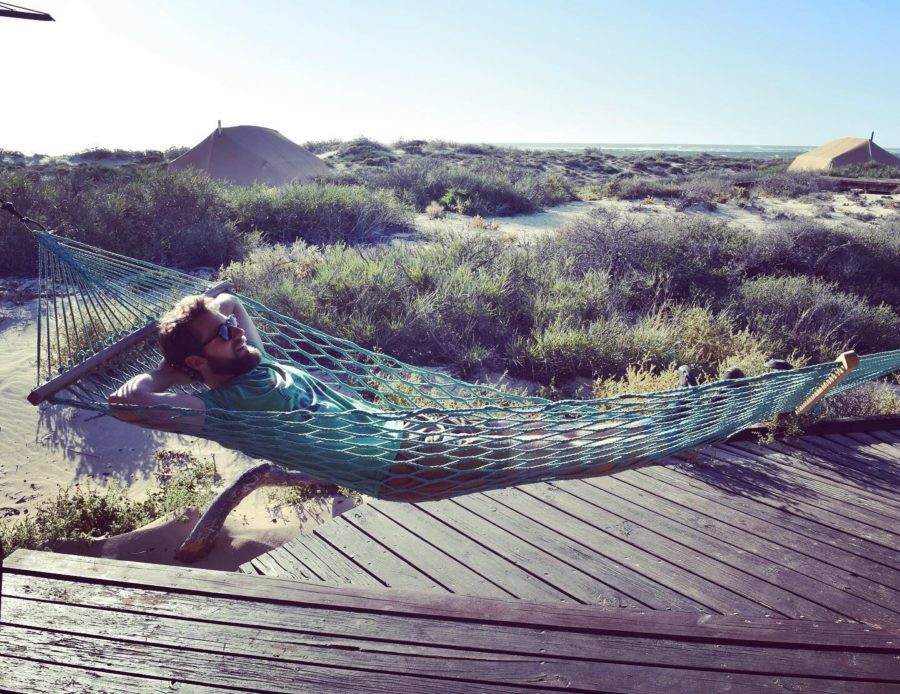 enrico lying in a hammock with sandy dunes in the background