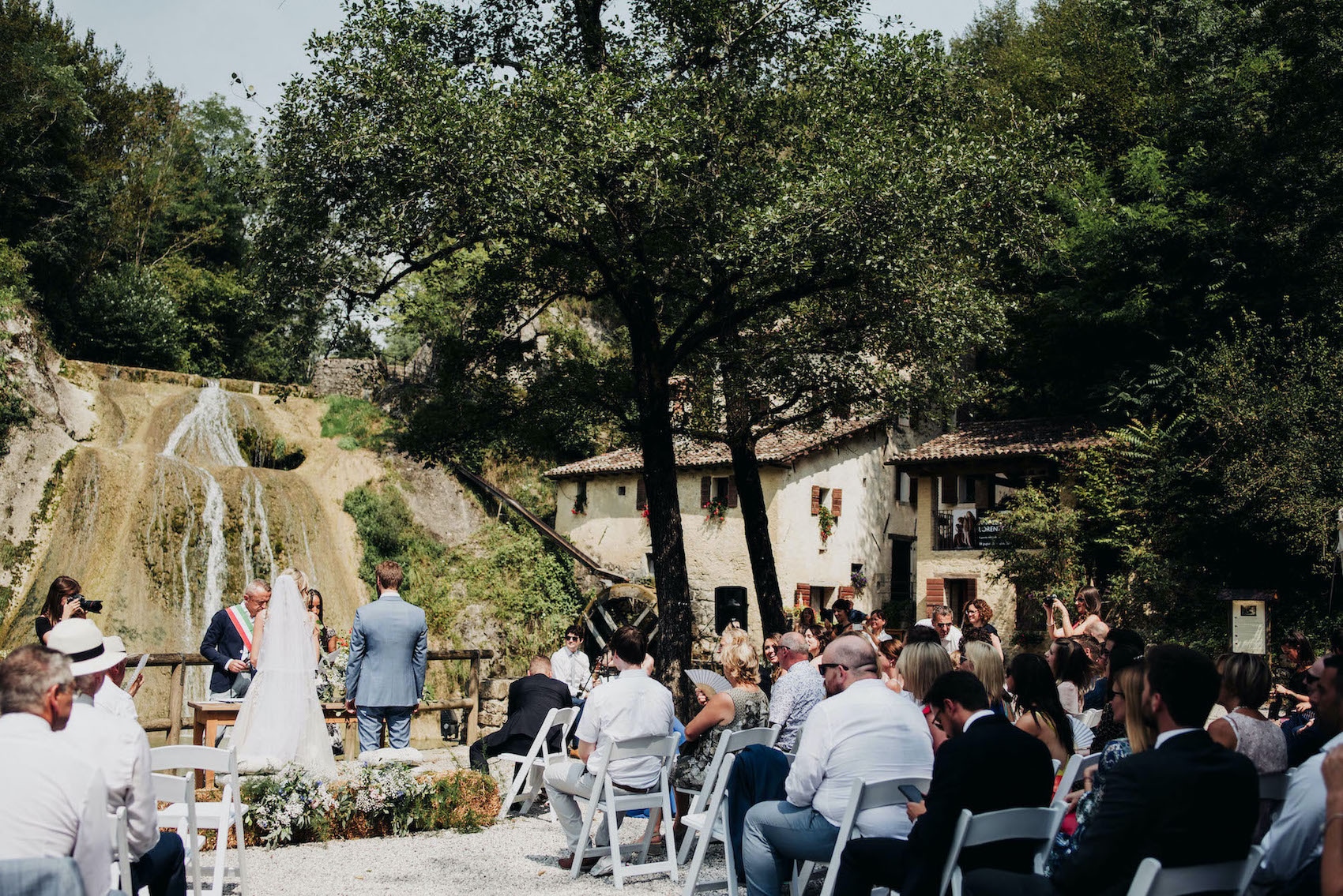 Hayley and Enrico saying their vows in front of a water mill 
