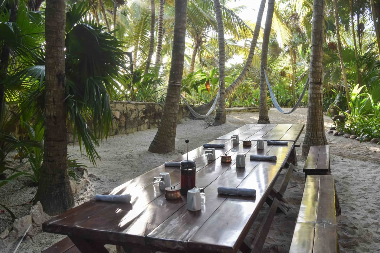 A long wooden table outside at an eco resort in Tulum. One of our favourite sustainable hotels. 