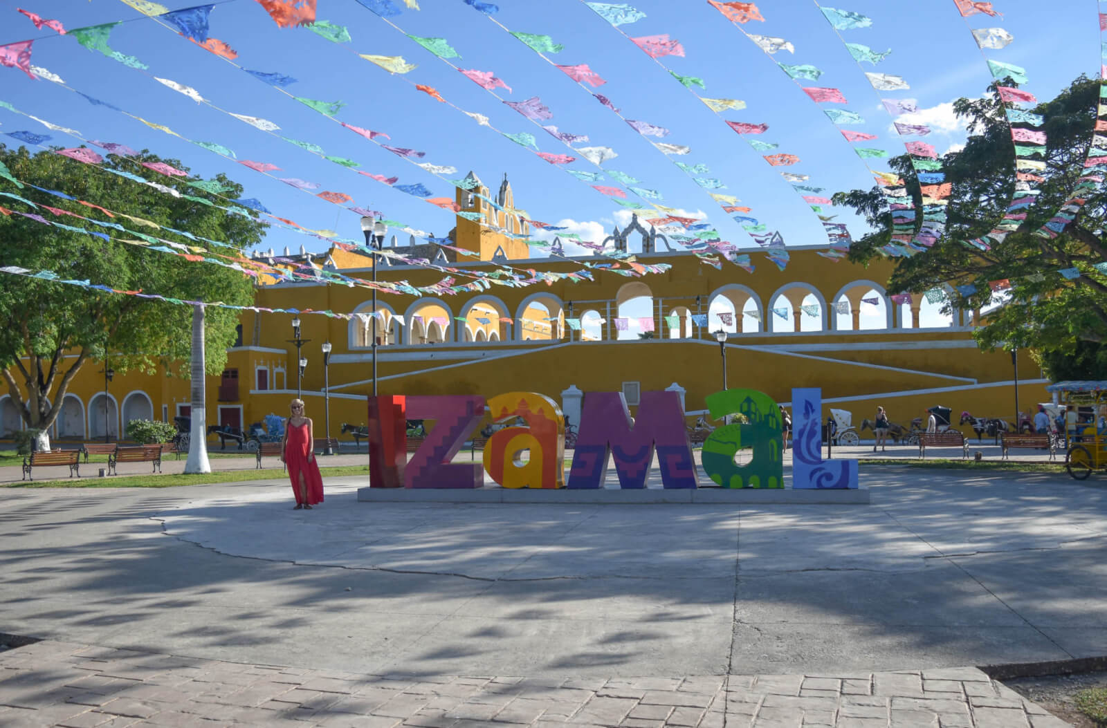Brightly coloured letter statues spelling Izamal in front of the monastery 