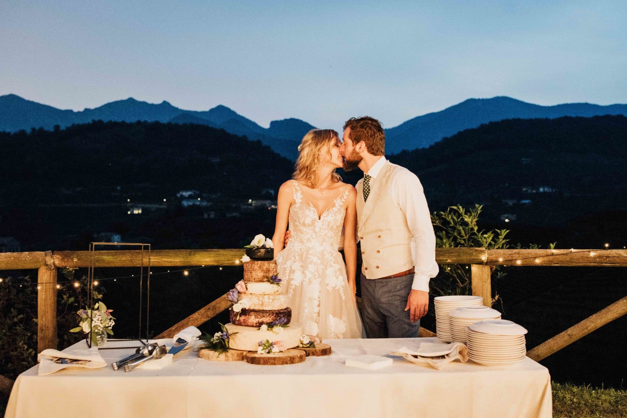 Hayley and Enrico standing behind a wedding cake of cheese