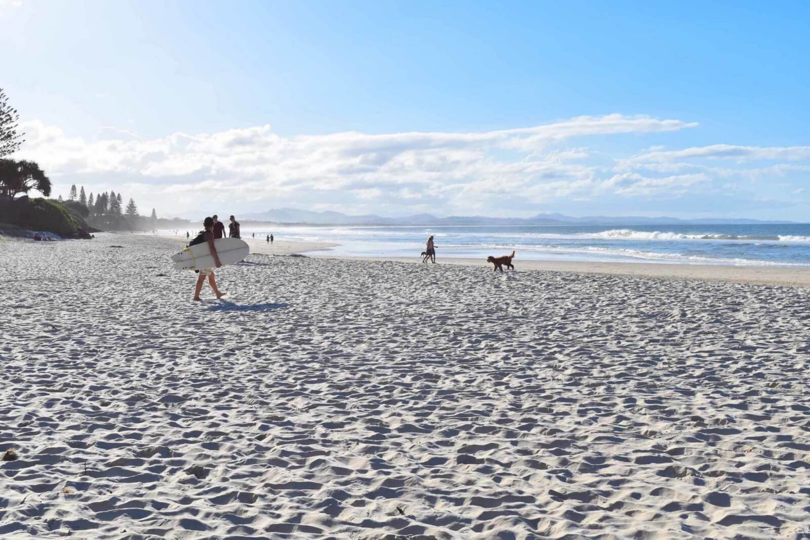 A surfer walks on teh sand on Belongil Beach in Byron Bay