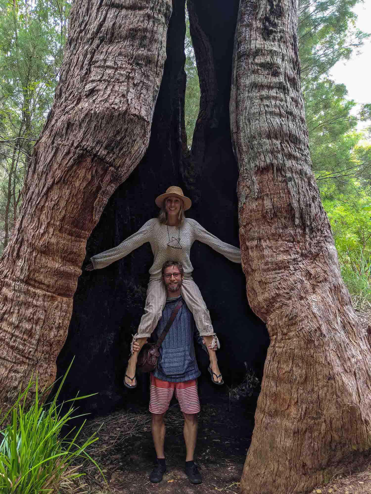 Hayley sitting on Enrico's shoulders inside a huge tree trunk 