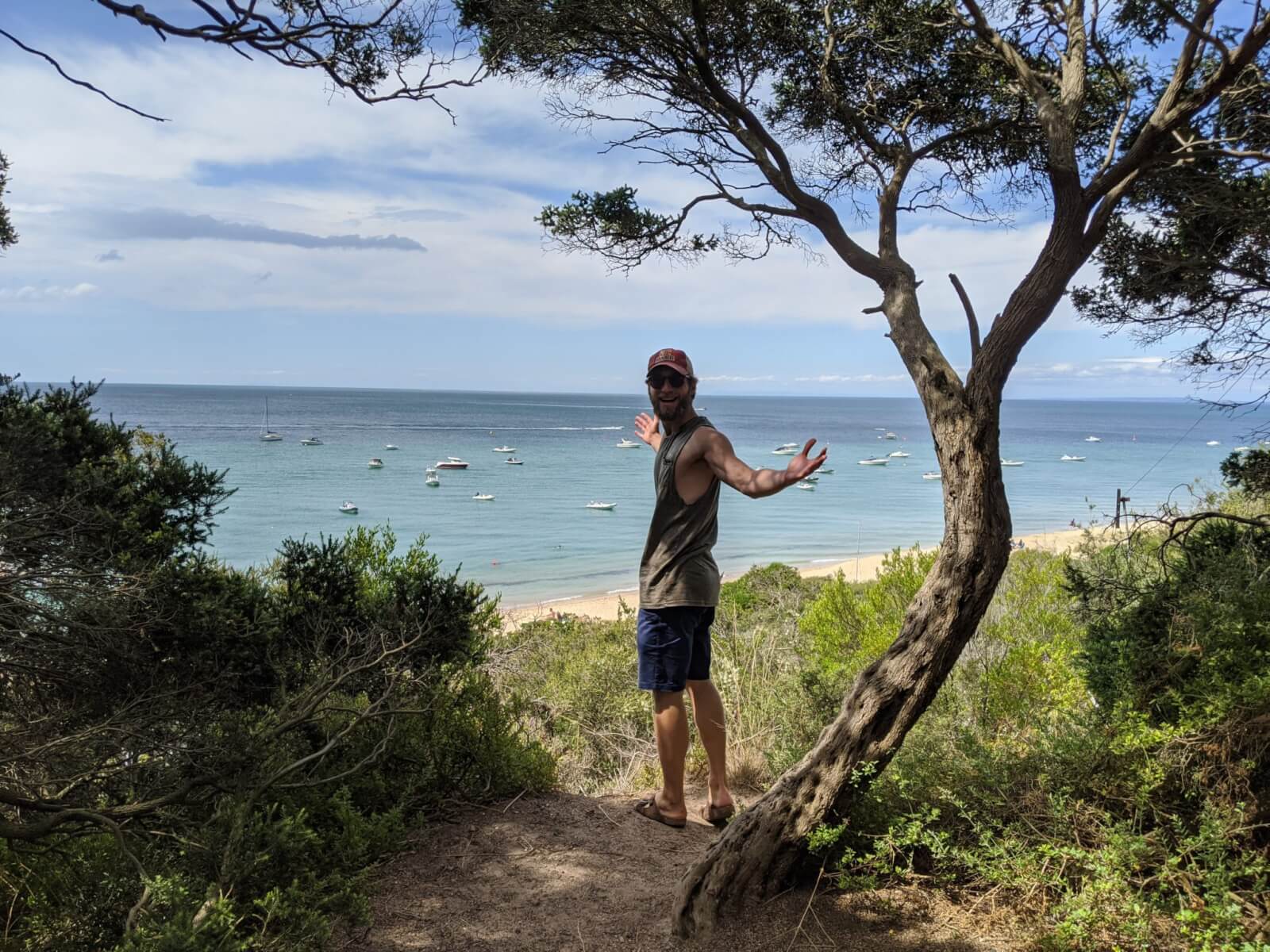 Enrico standing next to a tree in front of a beach. 