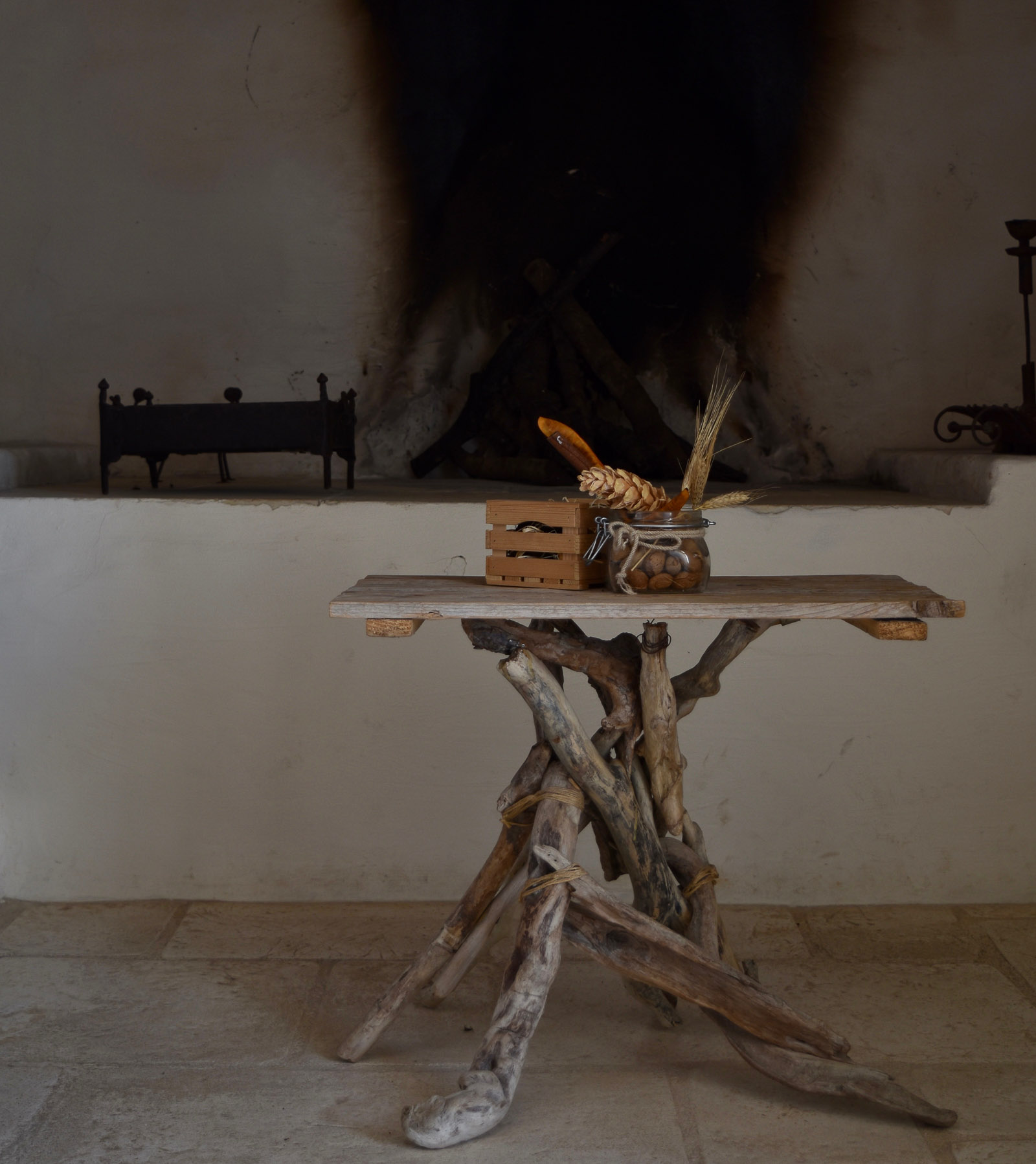 A wooden table with unique branch legs in front of a fire place