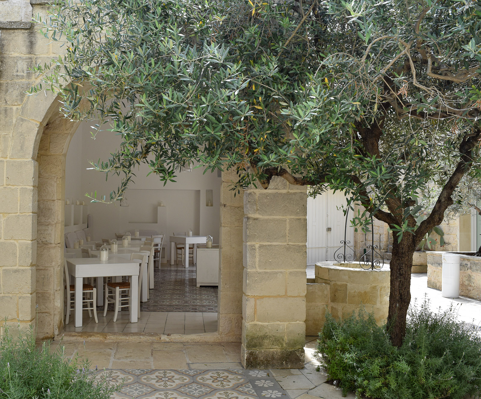 A terrace with olive trees and tables with candles 