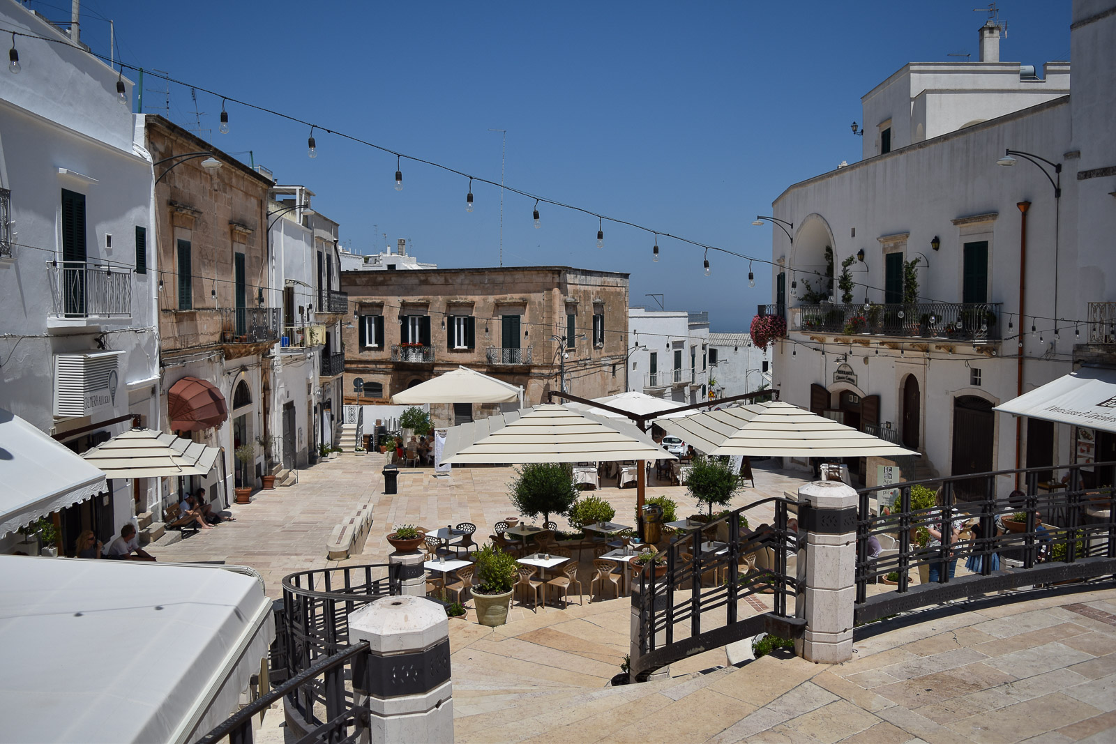 Umbrellas and tables and chairs in a piazza in Ostuni