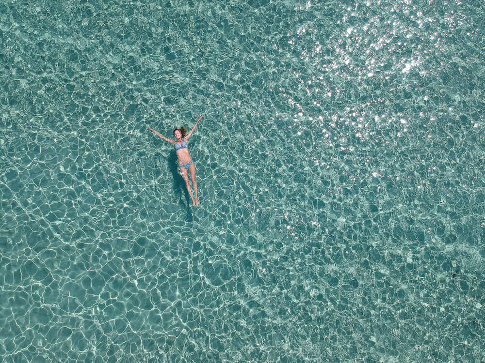Hayley floating in clear water shot from above