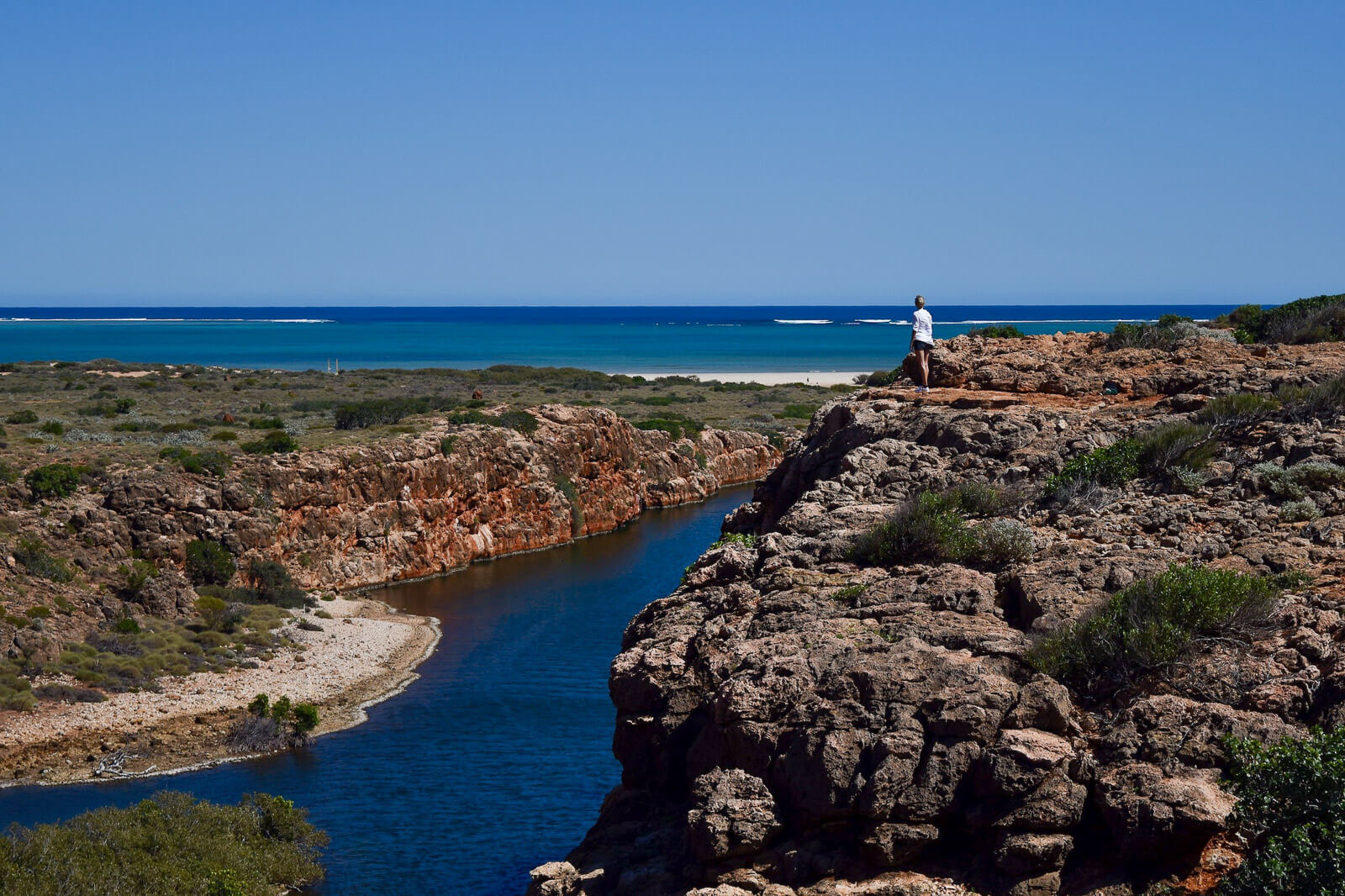 Hayley standing on a cliff by a river with the ocean in the background 