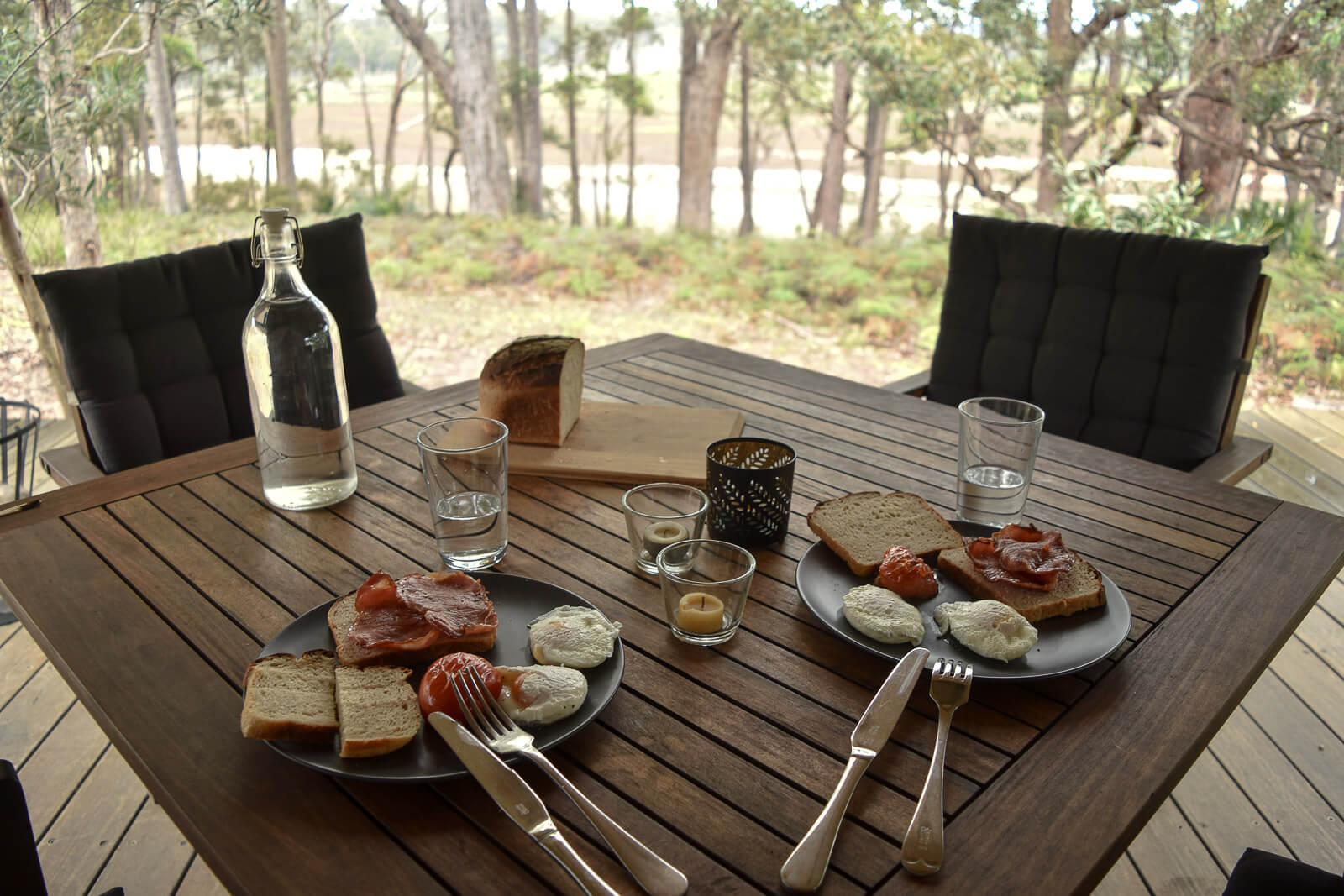 A table with plates of eggs and bacon, overlooking a lagoon