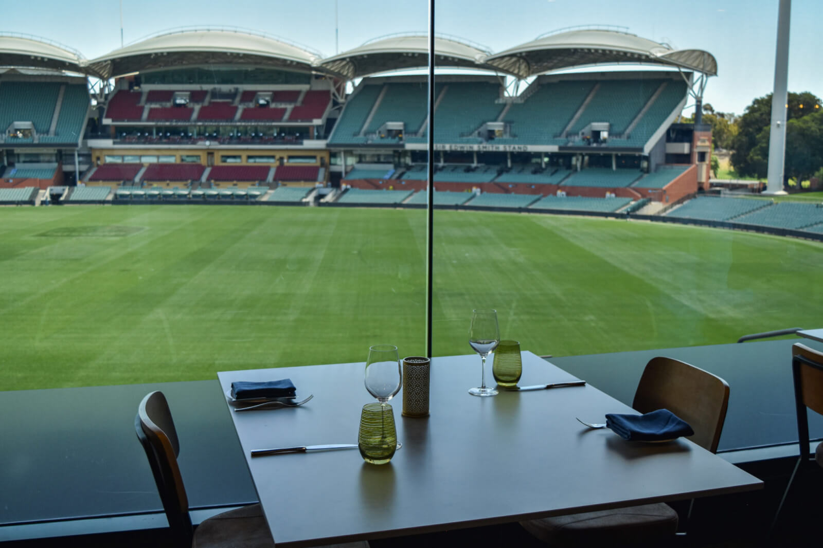 A dinner table set up in front of a cricket oval pitch