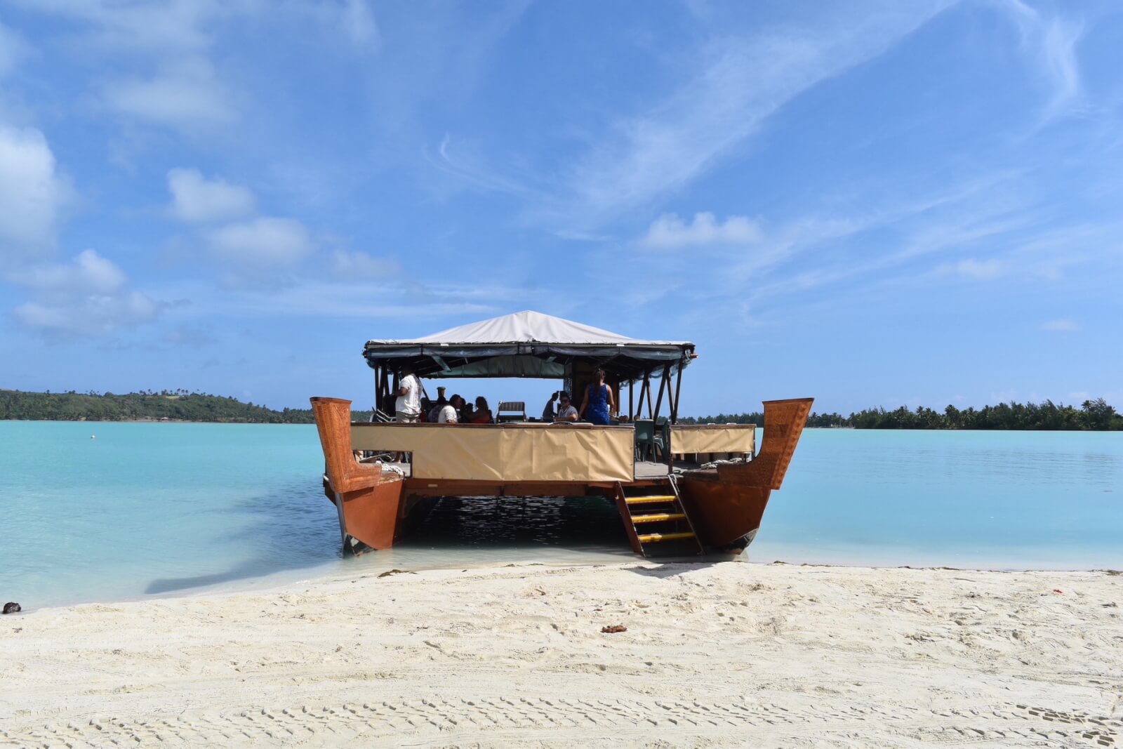 A large outrigger style boat on turquoise water. A must do on a Cook Islands itinerary.
