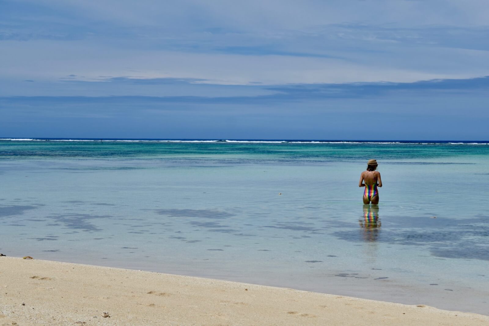 Hayley stands in the water wearing a rainbow swimsuit 