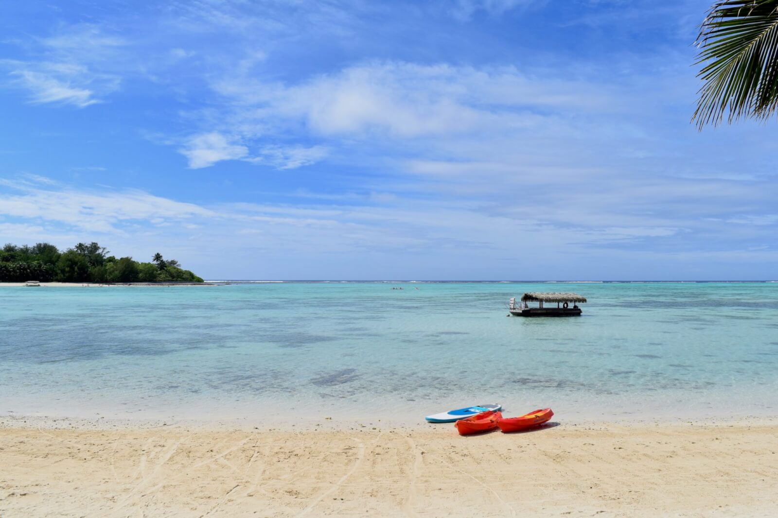 A golden sand beach and turquoise water with a red canoe 