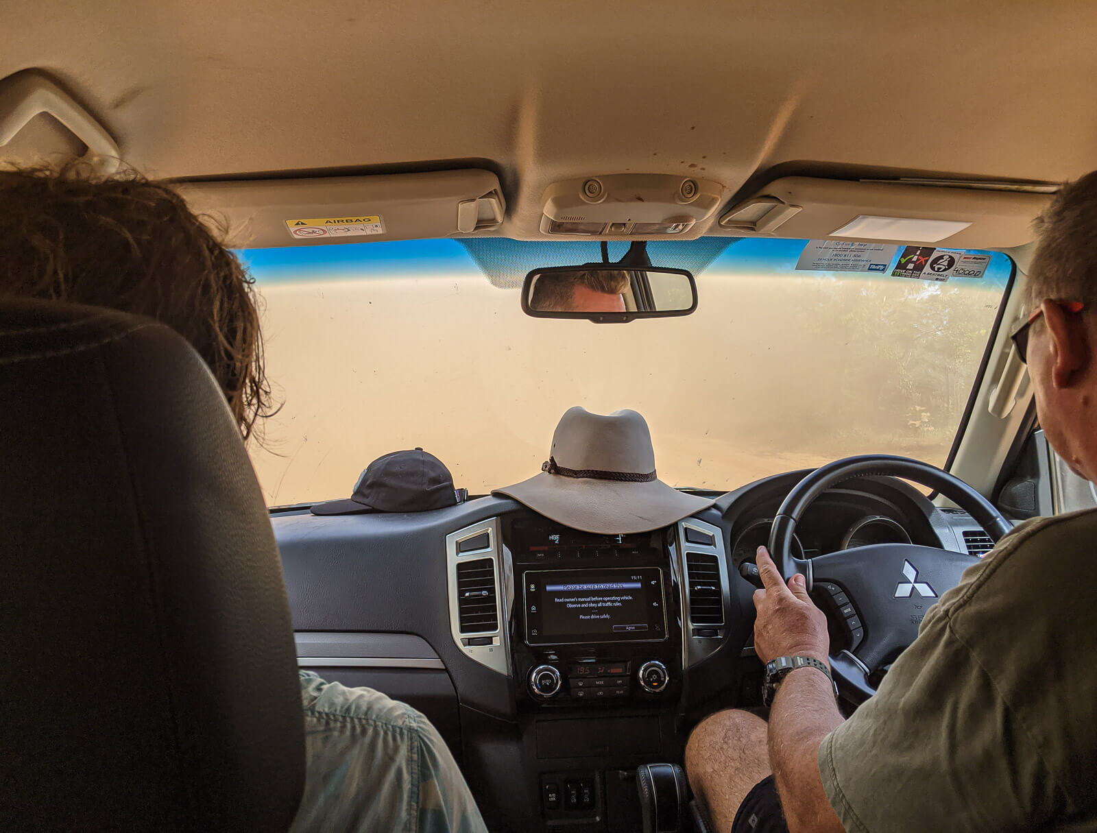 Looking out the windscreen of a car and only red sand can be seen