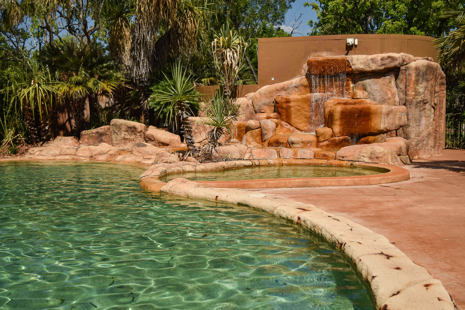 a lagoon style swimming pool with a waterfall 