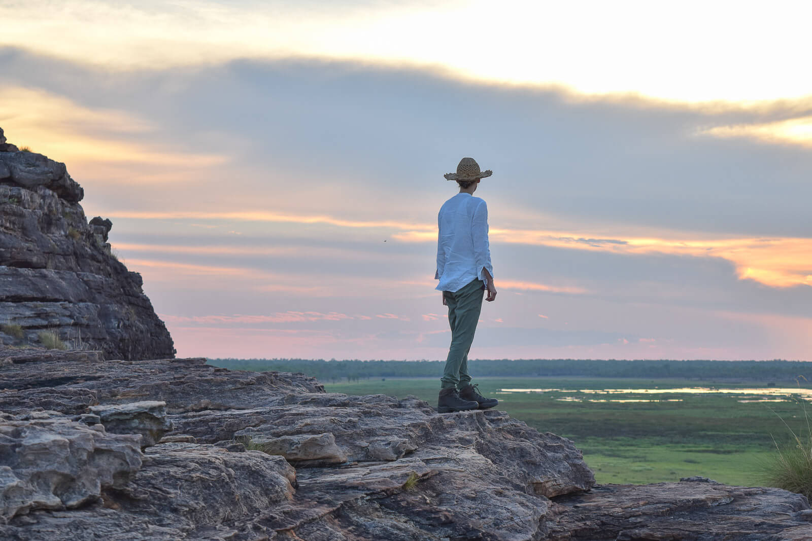 Hayley standing on a rocky cliff looking at the sunset in Kakadu National Park 