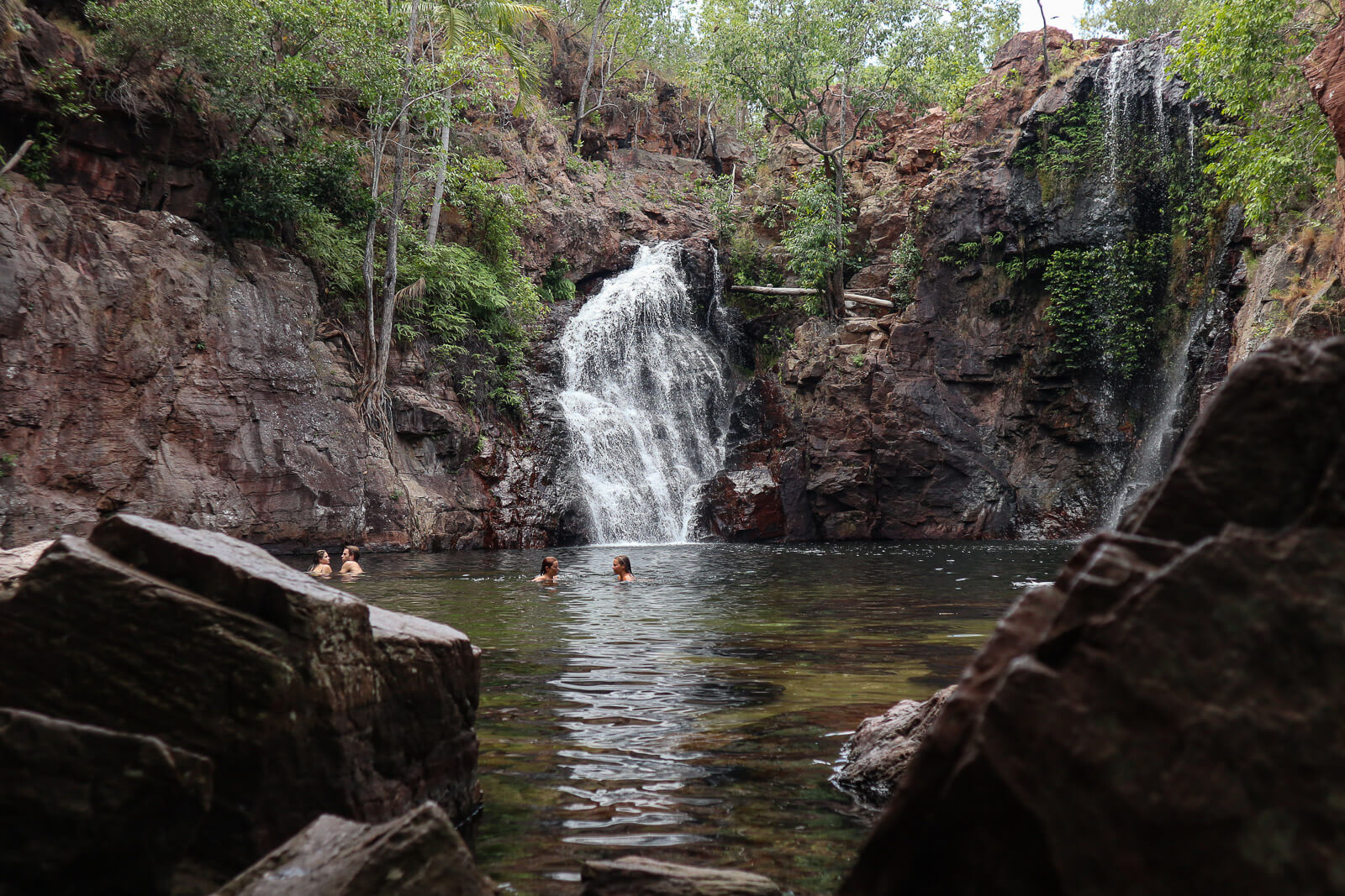 People swimming in a pool at the bottom of Florence Falls in Litchfield National Park 