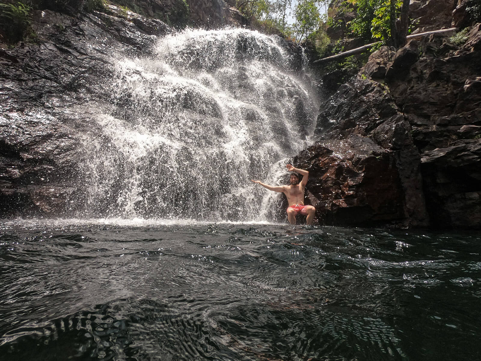 Enrico sitting on a rocky ledge in a waterfall 