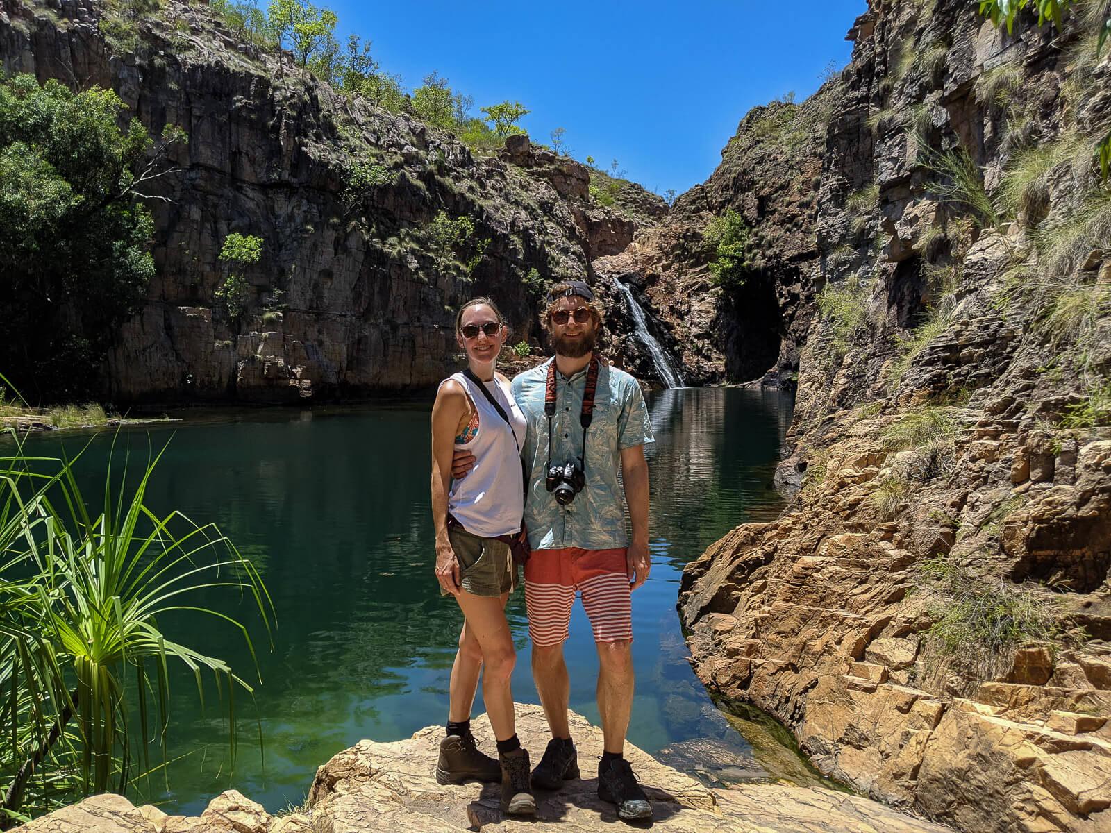Hayley and Enrico standing in front of a big rockpool with a waterfall in the background 