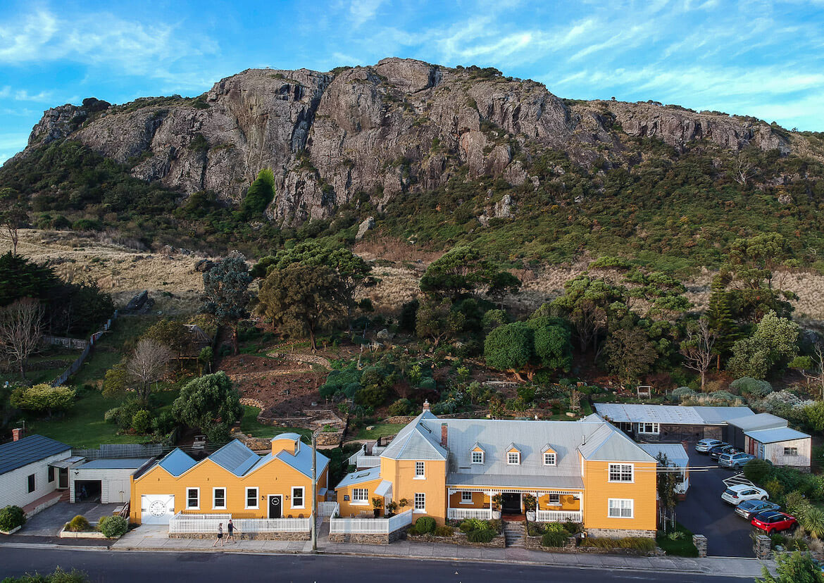 A yellow building with a huge rock in the background