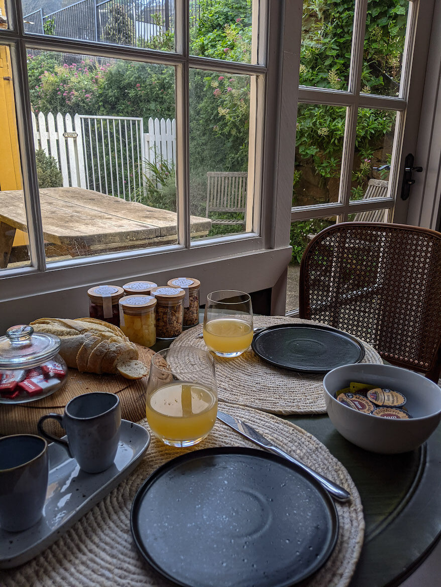 A beautiful continental breakfast set up on a table with a courtyard view 
