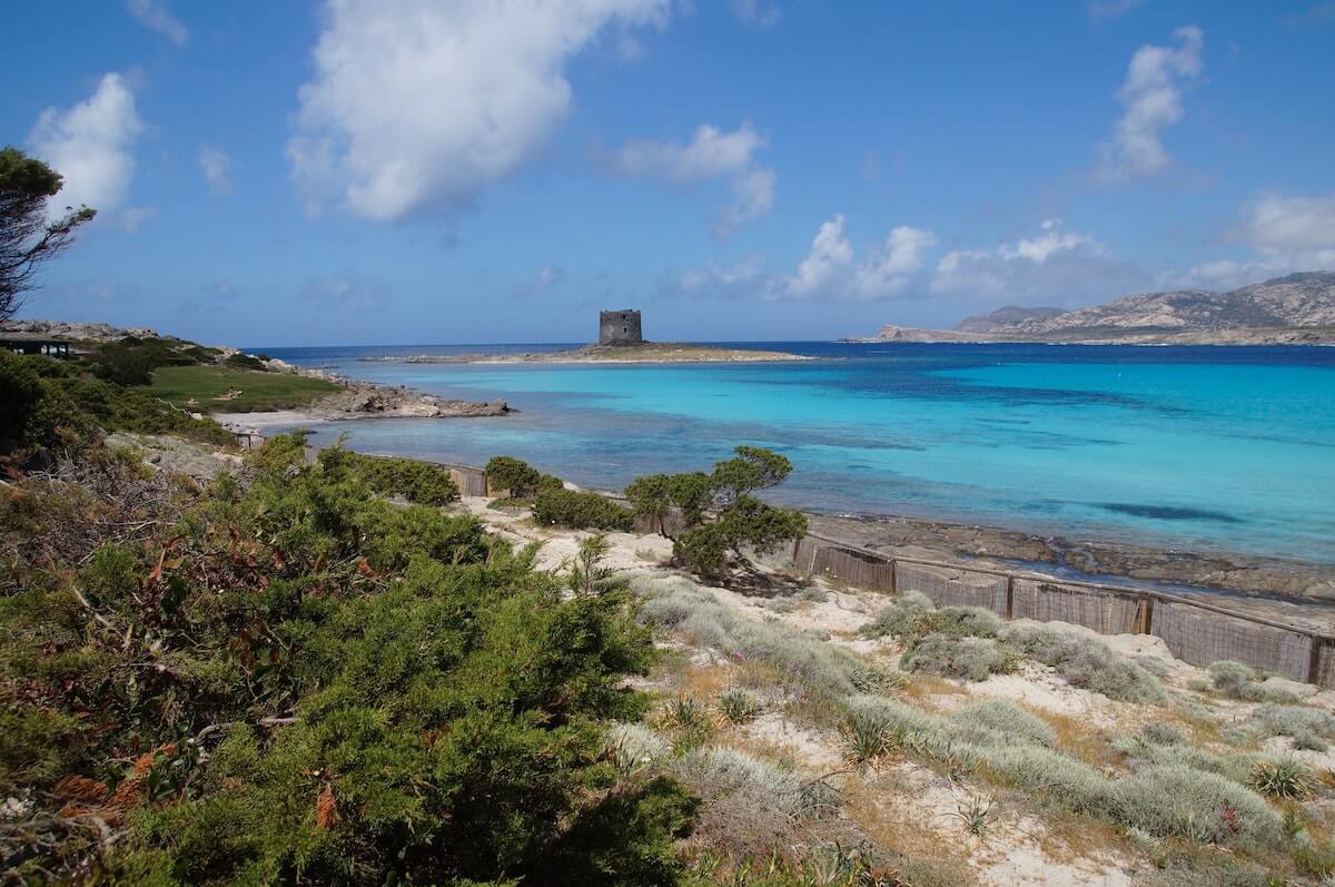 A tower on an island surrounded by blue water 